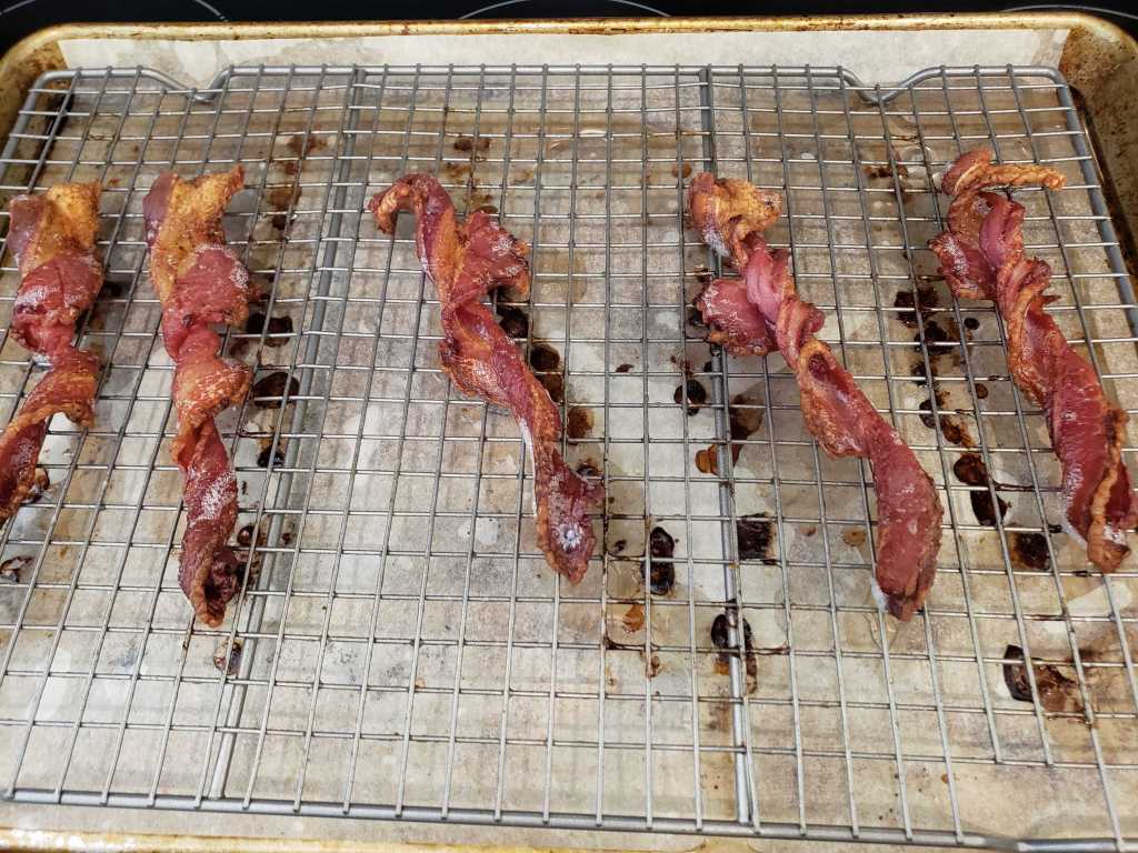 Image of cooked bacon laying across a cooling rack.