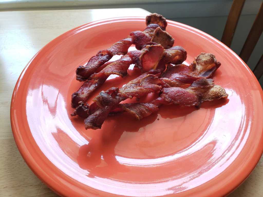 Image of cooked, twisted bacon laying on a plate.