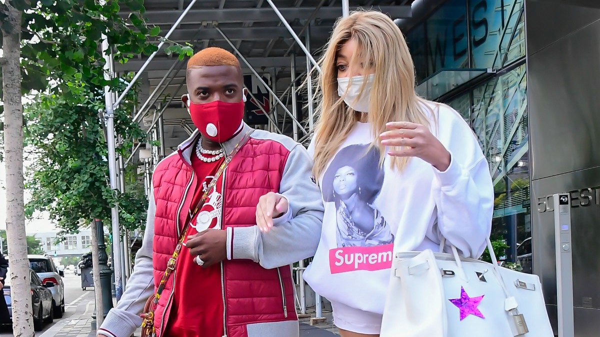 Ray J, in red, walks arm in arm with Wendy Williams, in white, on a NYC sidewalk