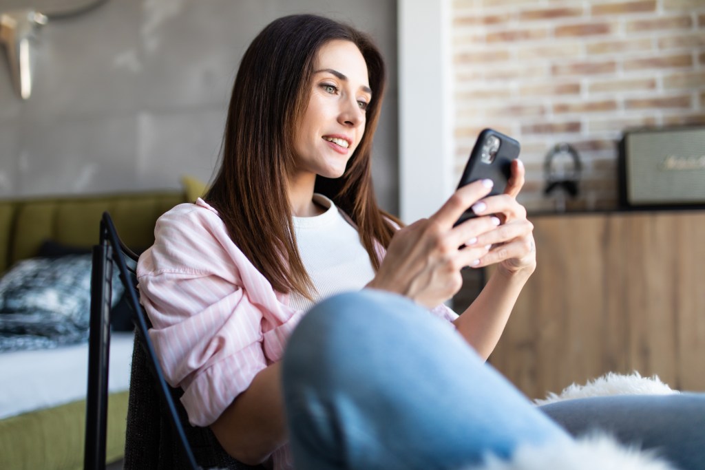 Image of young woman on phone while sitting on a chair.