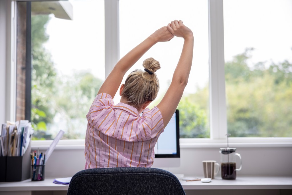 Image of woman stretching at desk