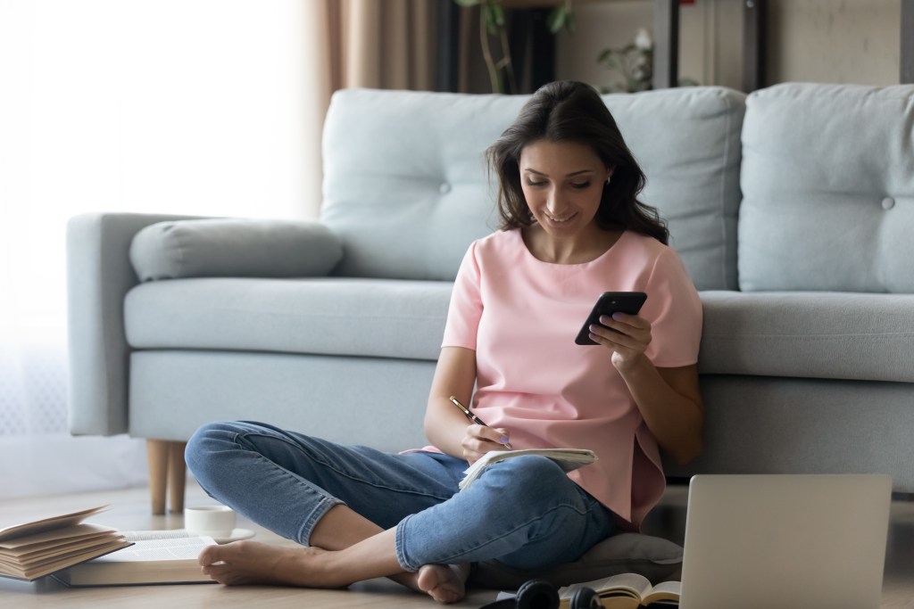 Image of woman on phone while sitting on the floor.