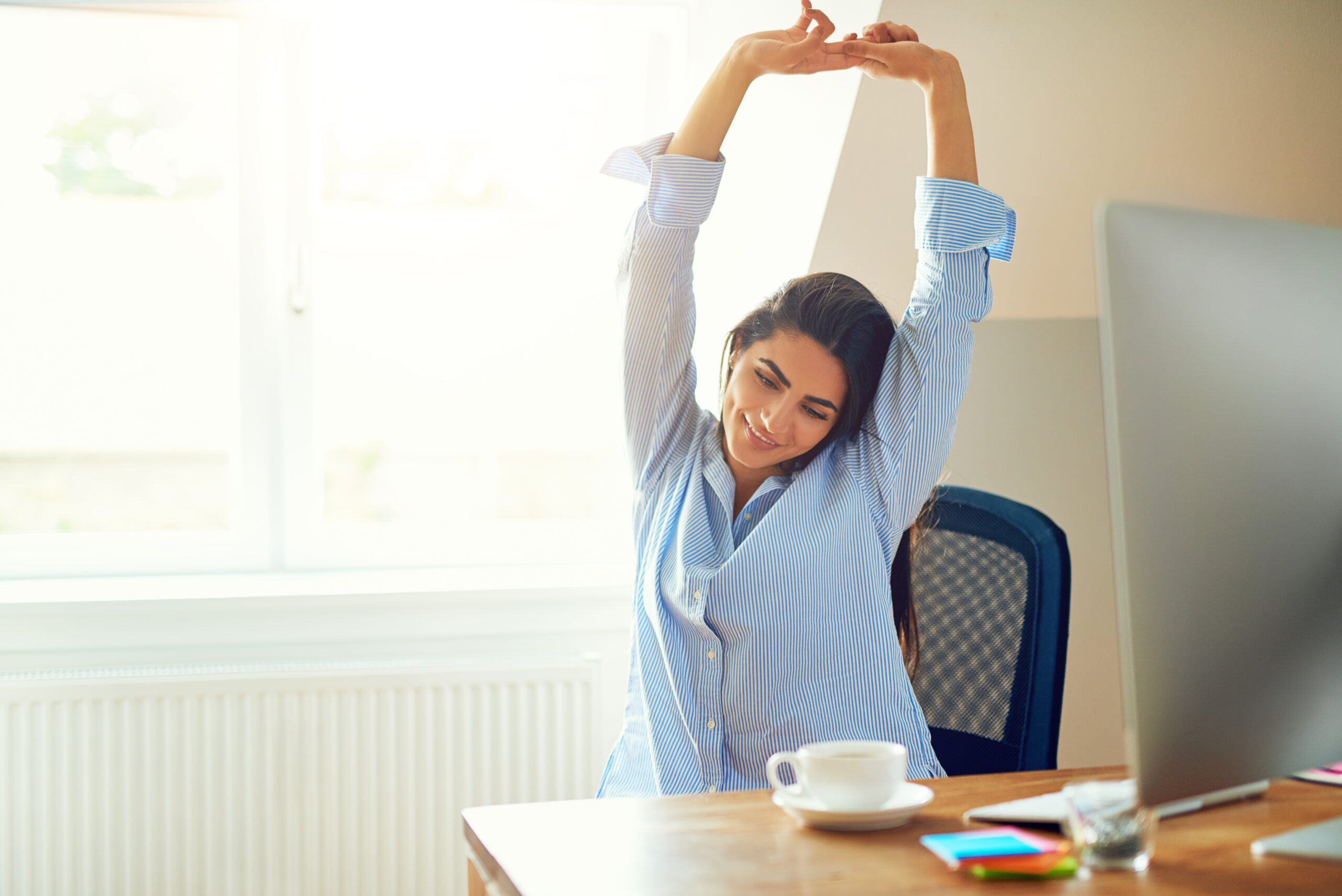 Image of woman stretching at desk