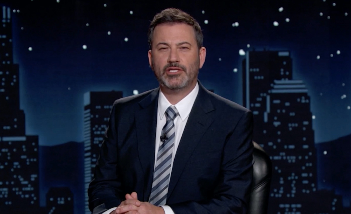 Jimmy Kimmel in a suit sitting at a desk