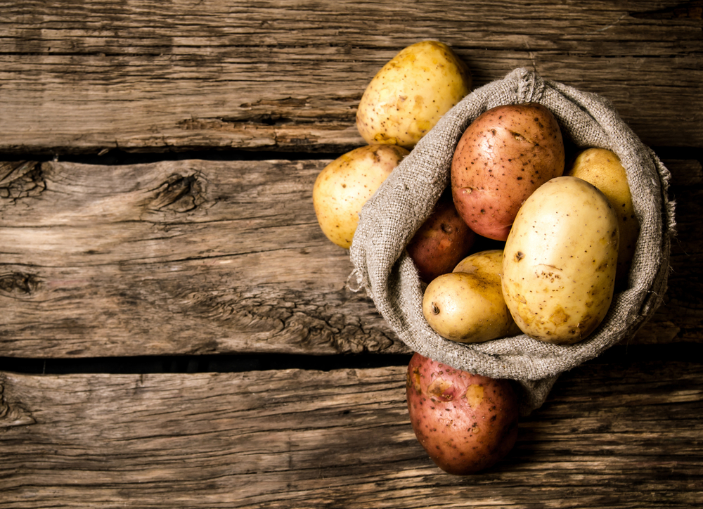 Russet and Yukon gold potatoes on a wooden table. 