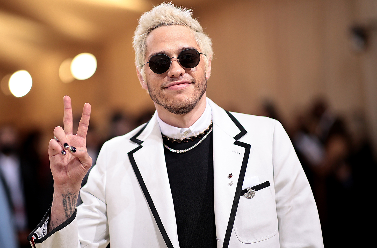 Pete Davison flashing a peace sign in a white jacket and sunglasses