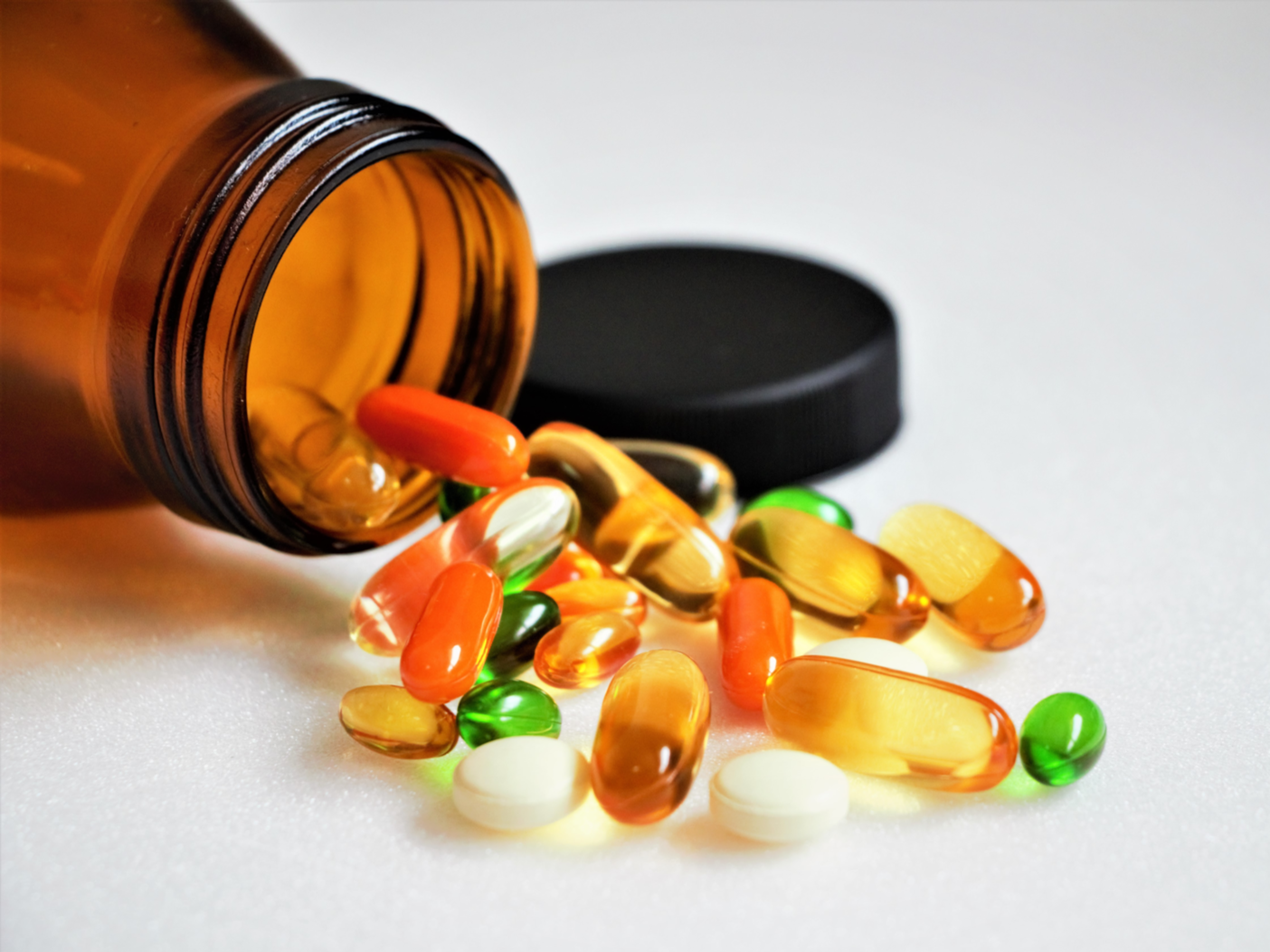 Close up vitamins and supplements on white background with a brown bottle. Including Vitamin c, vitamin E, vitamin D3, salmon oil, fish oil and co enzyme Q10 capsules.