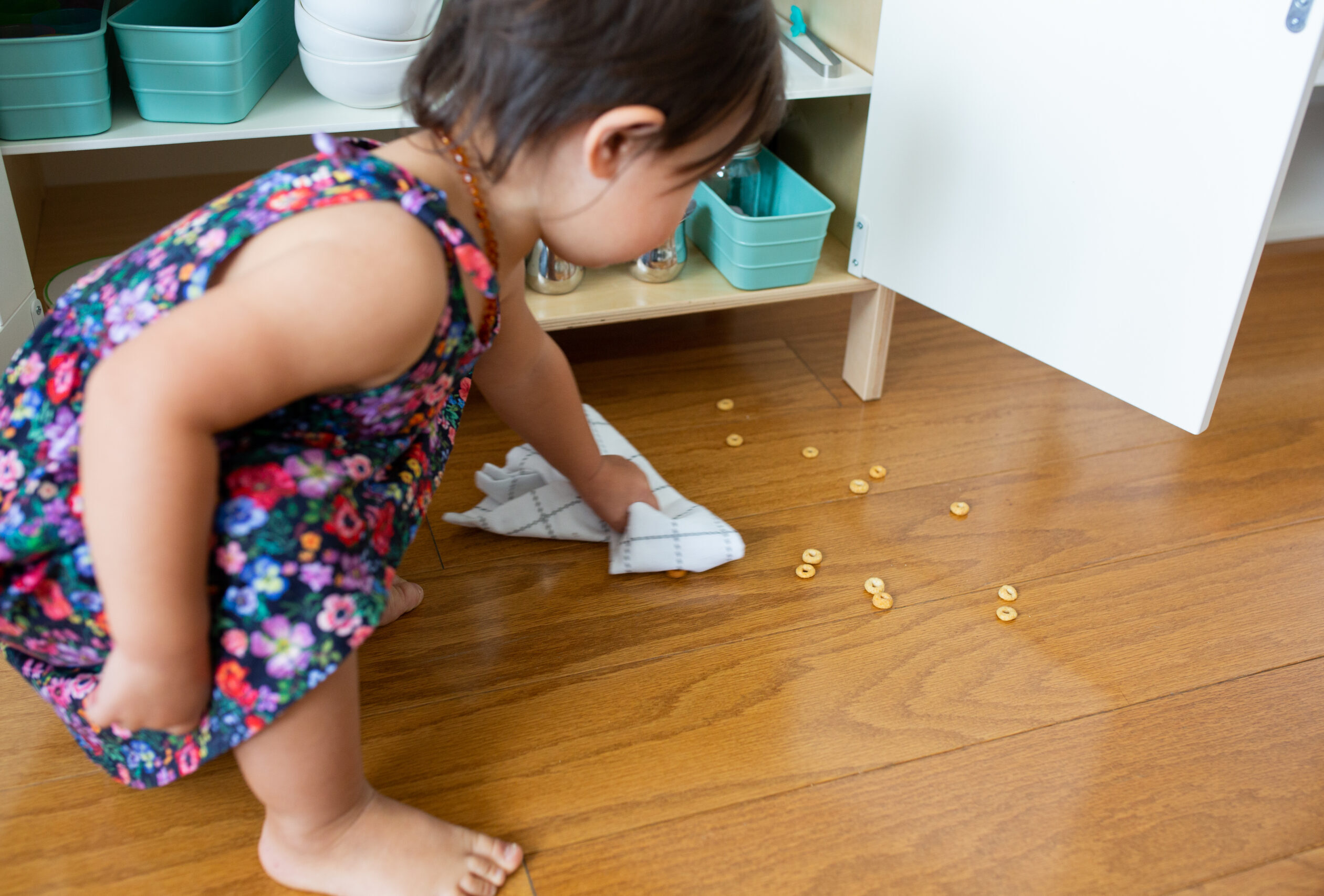 Toddler picking up cheerios off the floor.