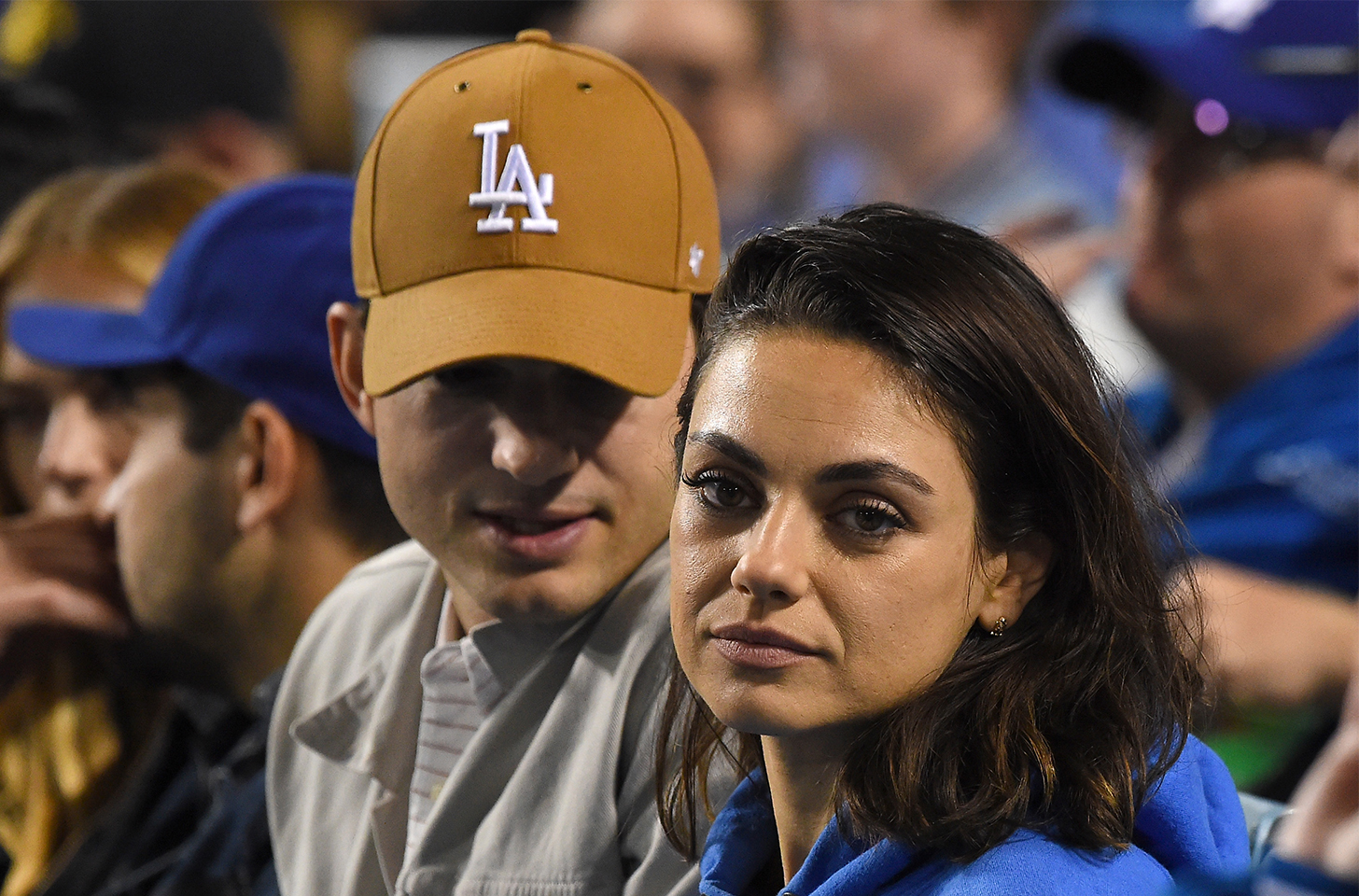 Ashton Kutcher sitting behind an annoyed-looking Mila Kunis