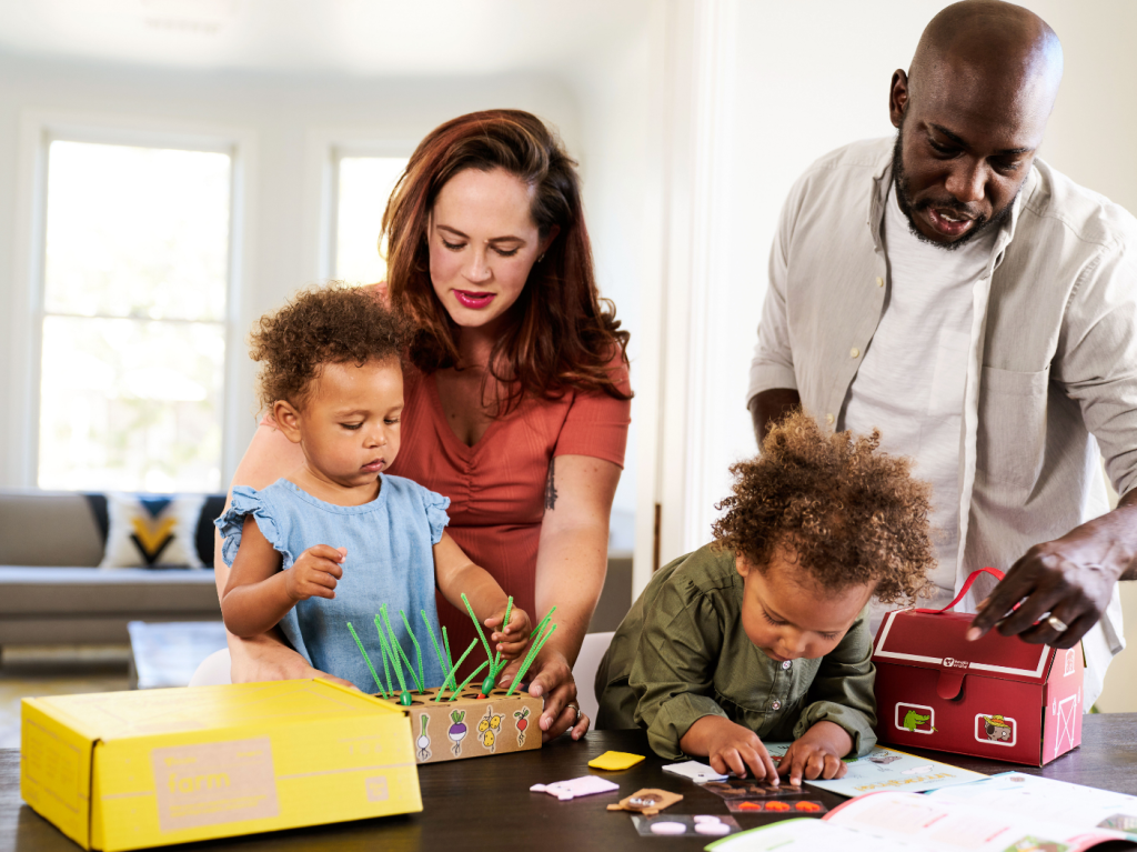 Parents helping two kids play with KiwiCo activity