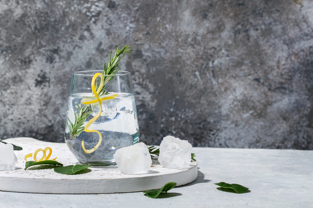 Gin and Tonic drink served with ice, lemon zest and fresh rosemary.