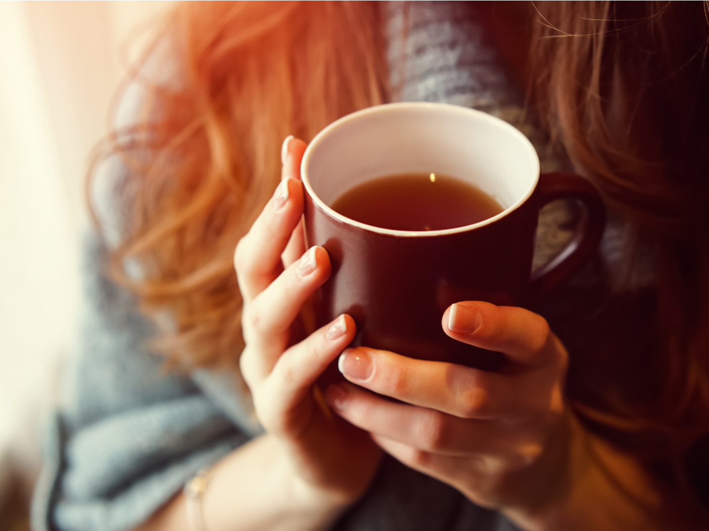 Drink Tea relax cosy photo with blurred background. Female hands holding mug of hot Tea in morning. Young woman relaxing tea cup on hand. Good morning Tea or Have a happy day message concept.