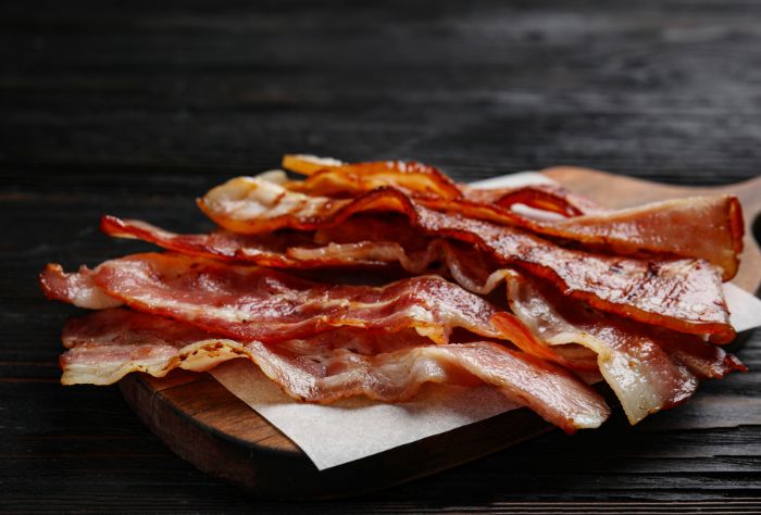 A cutting board with several pieces of cooked bacon