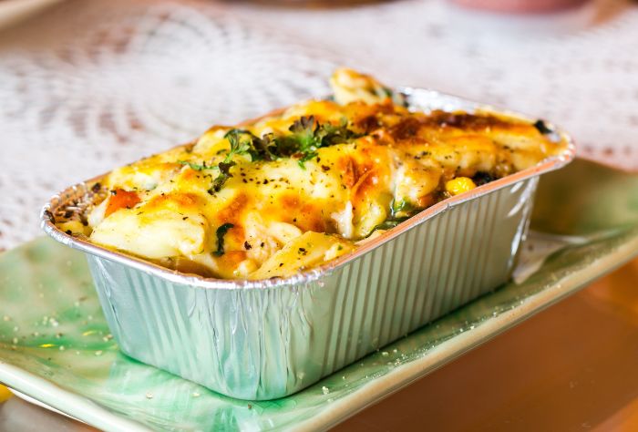 An aluminum foil pan with food in it sitting on a green plate