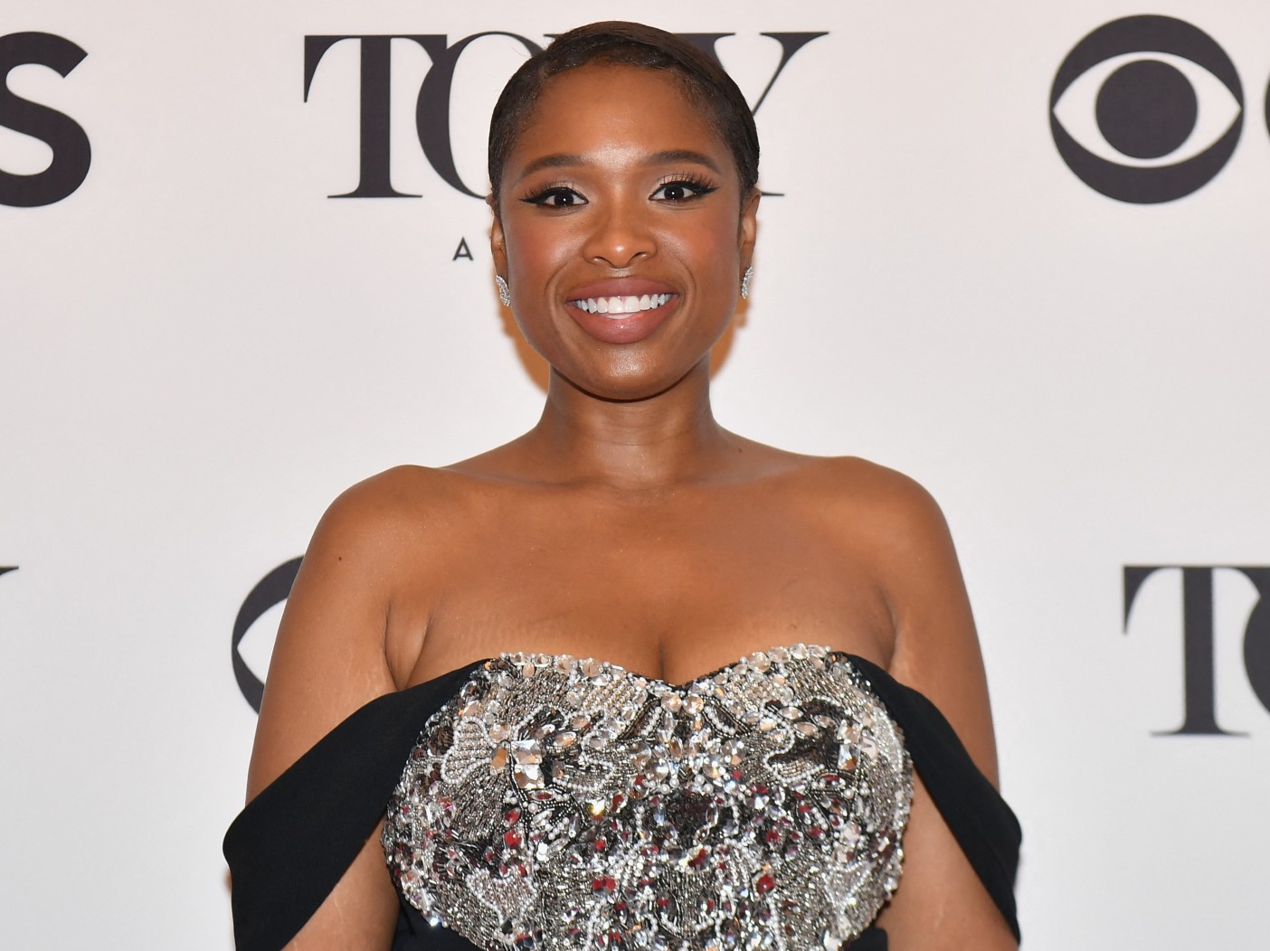 Jennifer Hudson smiles while wearing silver and black gown