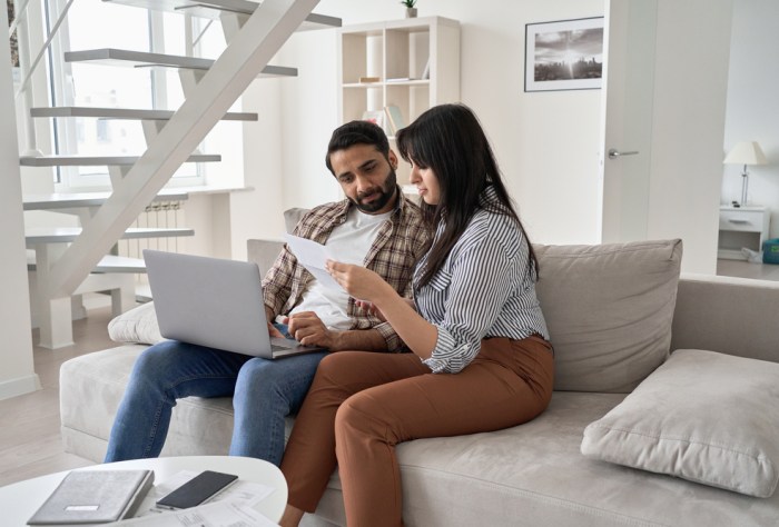 Couple sitting on couch with a laptop and papers