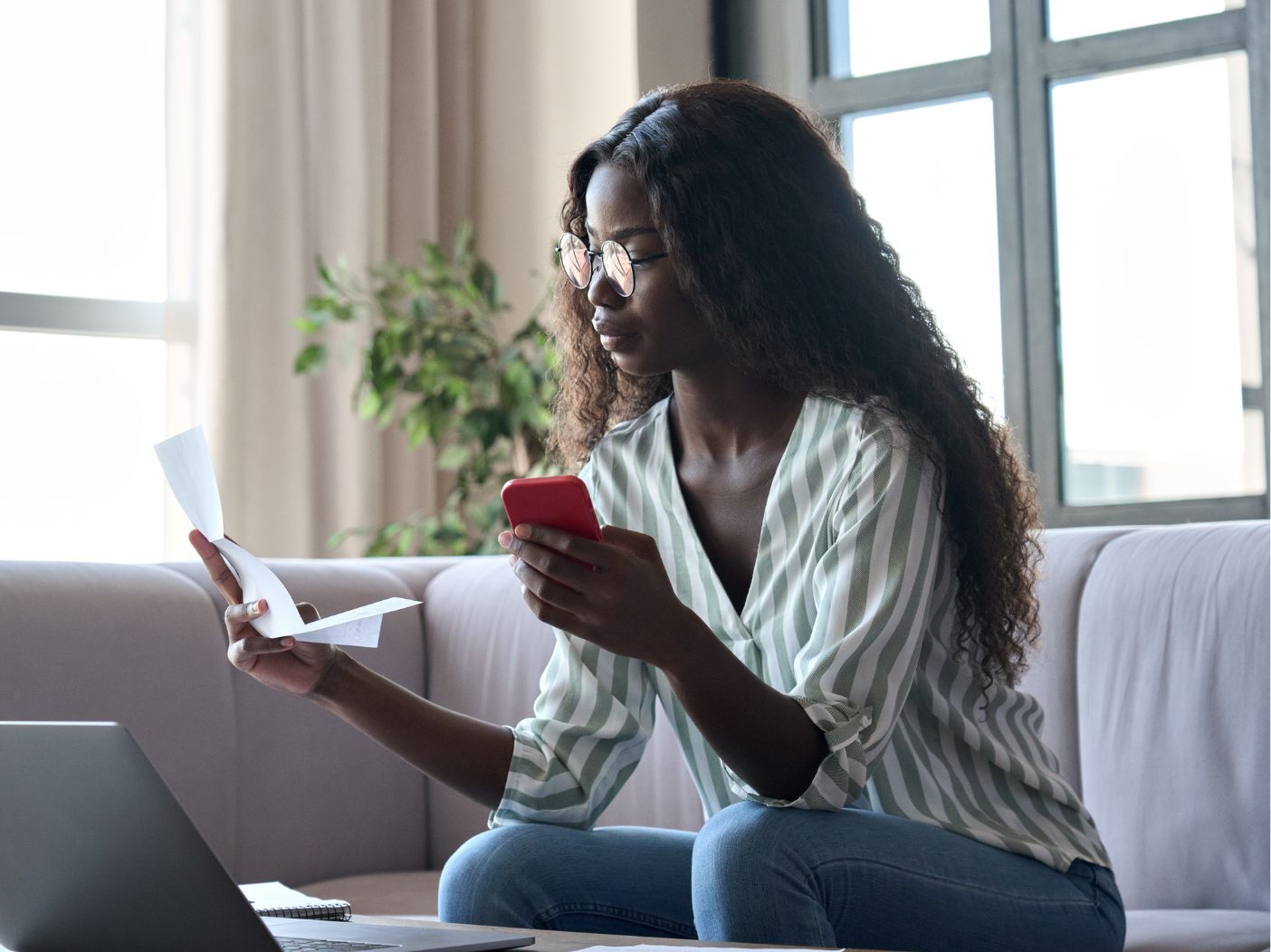 black woman with long hair examining document and phone