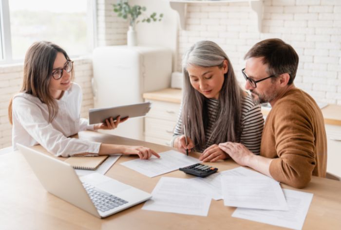 Middle aged couple sit with financial planner at table