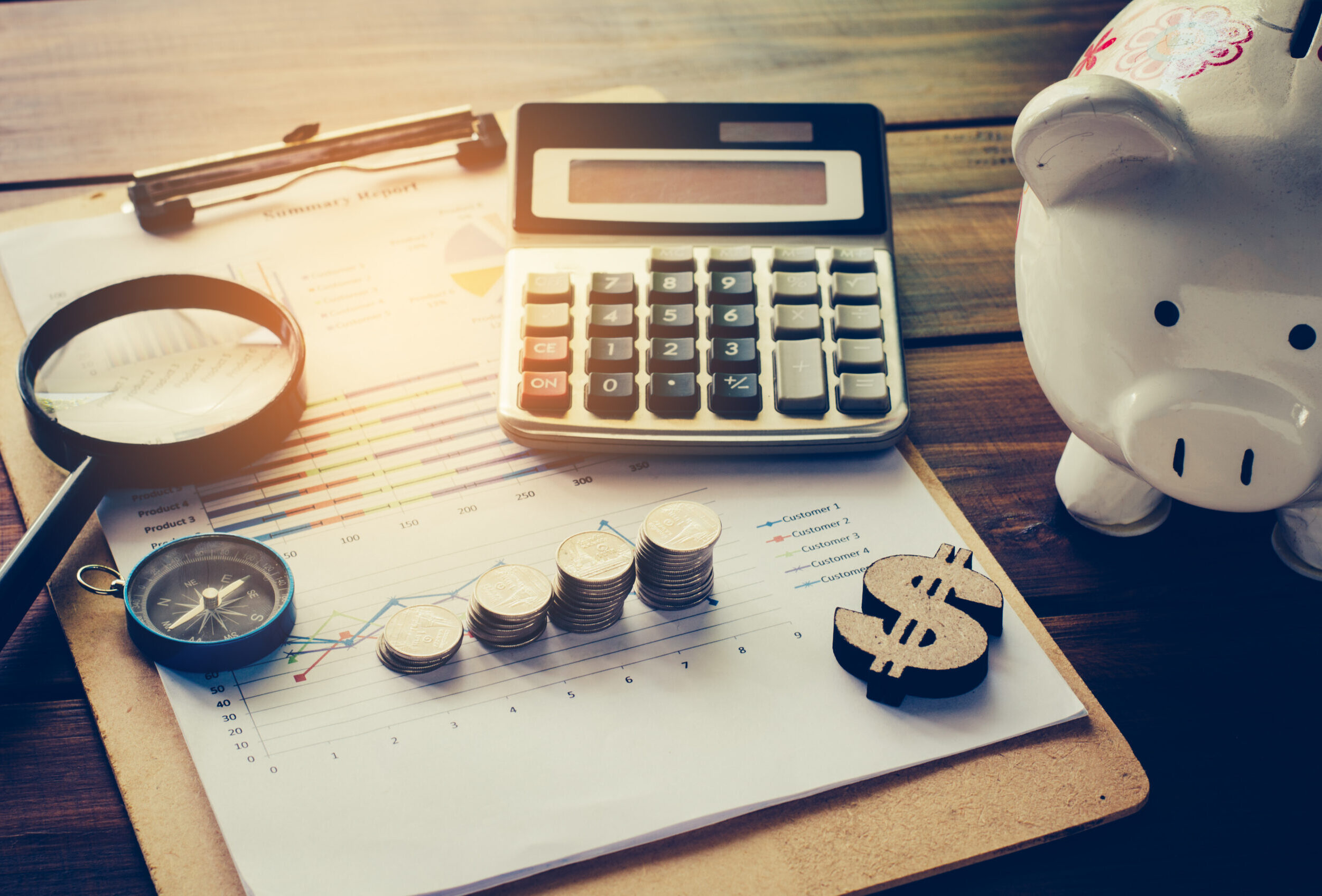 A clipboard with graphs, stacked coins, a calculator, and other items signifying financial planning.