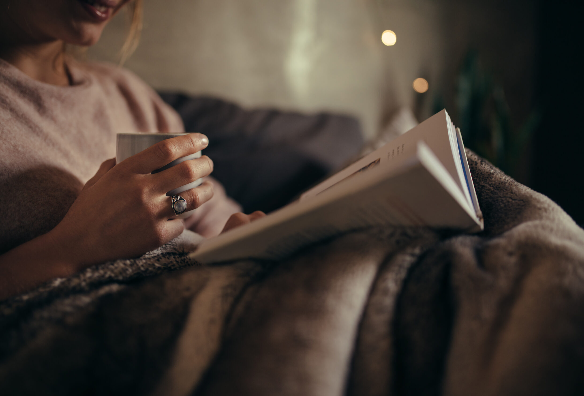 A woman in bed at night enjoying a good book.