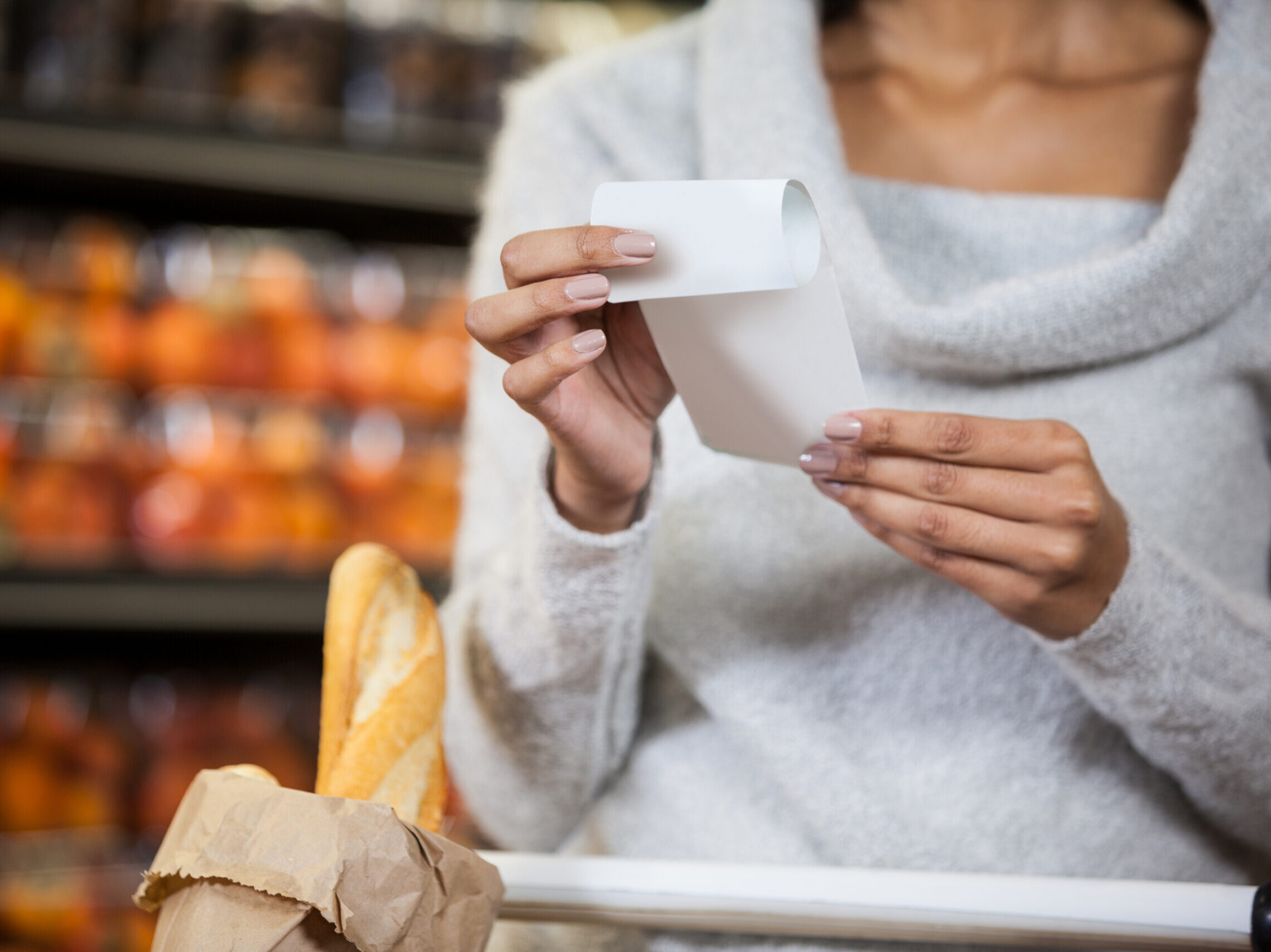 A woman at the grocery store looking at a recipt.