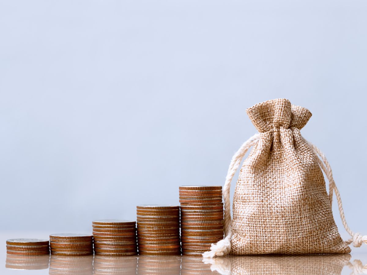 Stacks of coins sitting beside of a bag of money