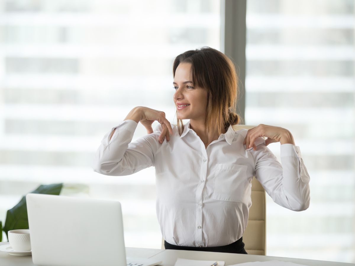 Woman sitting upright with good posture and hands on shoulders