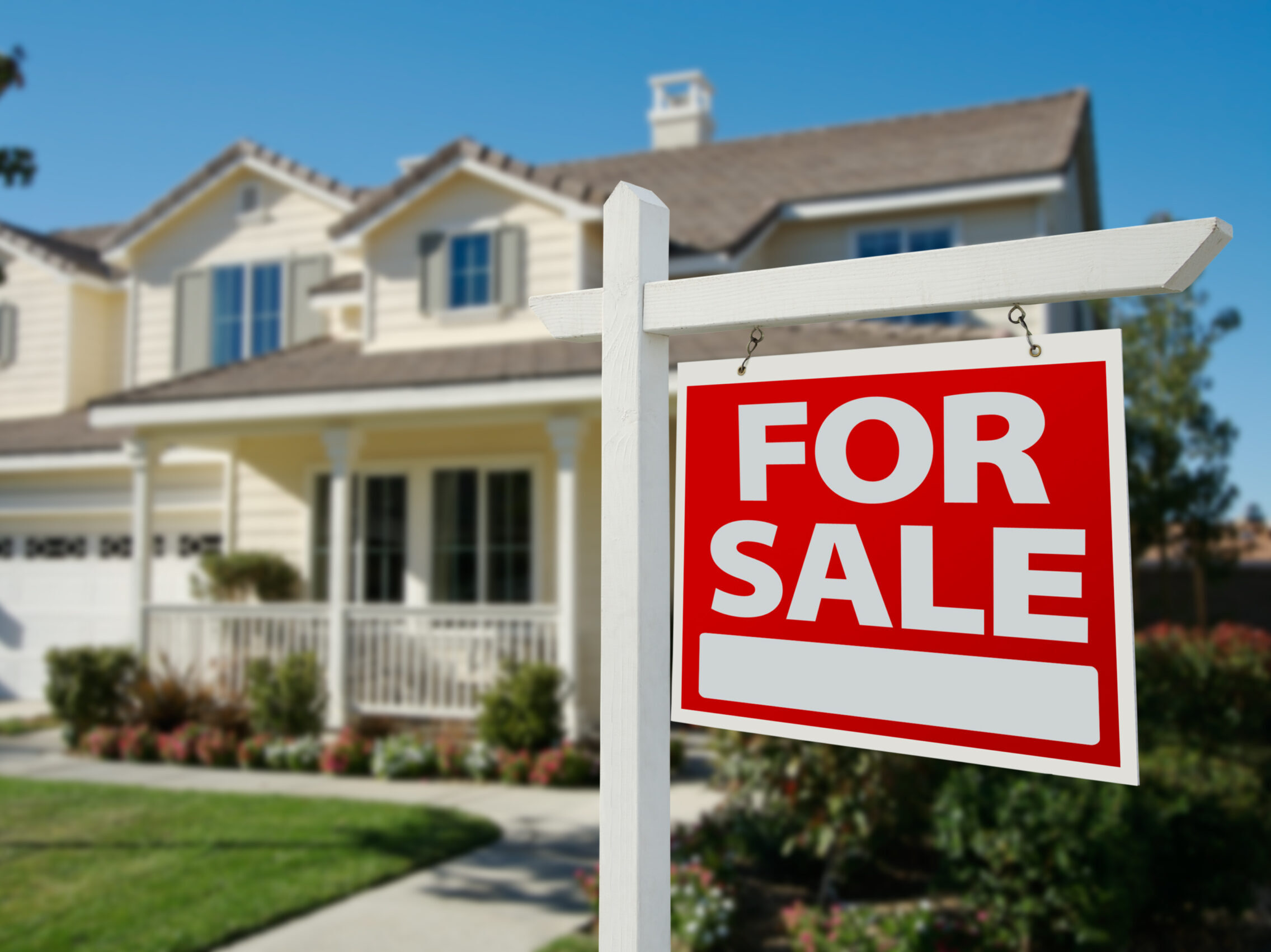 A for sale sign in front of an average suburban home.