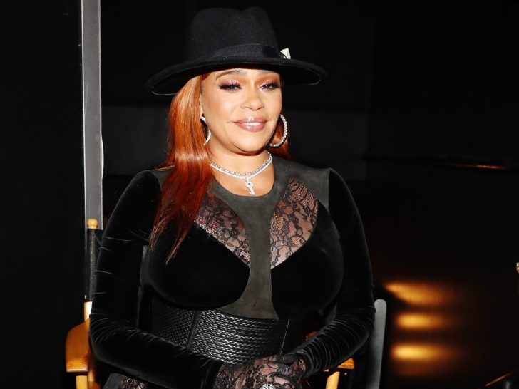 Faith Evans smiles in all-black outfit and matching hat