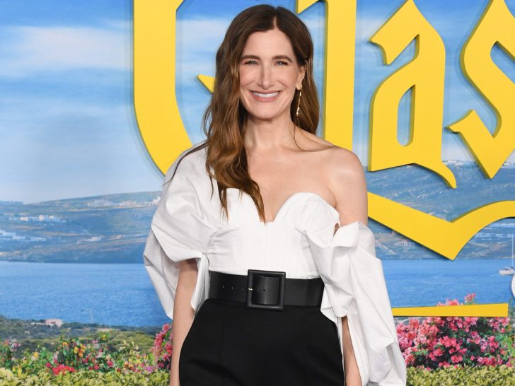 Kathryn Hahn smiles in white top and black pants