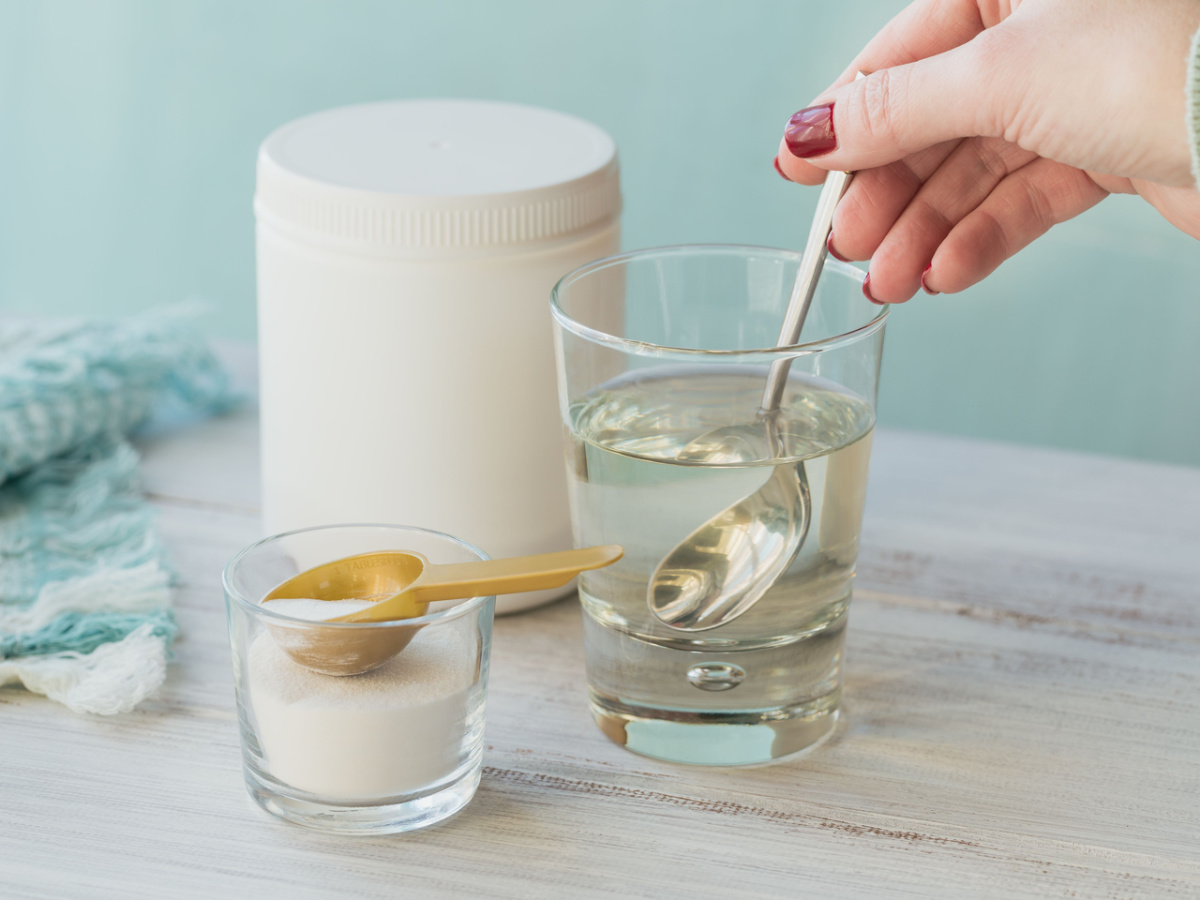 a hand mixing collagen powder into a glass of liquid