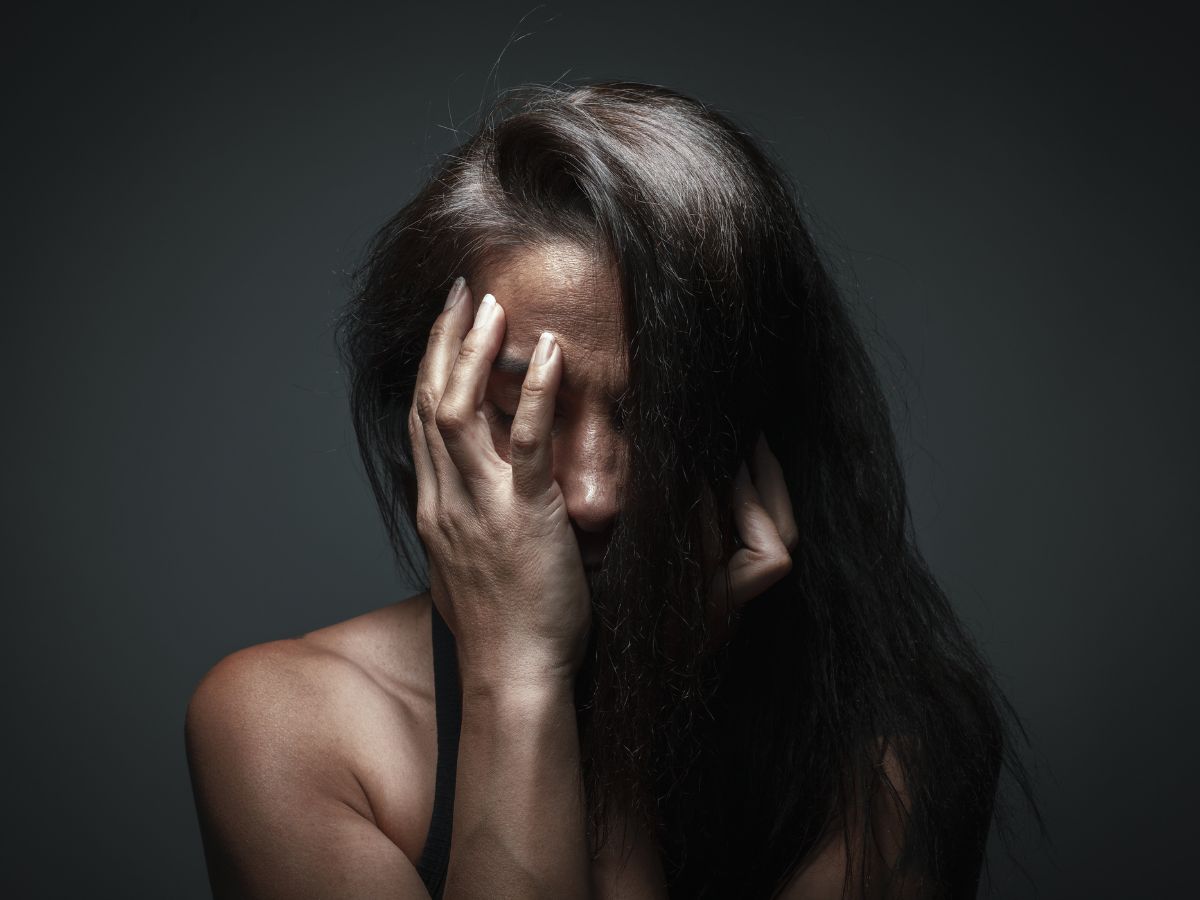 Midlife woman covering her face with her hands in despair