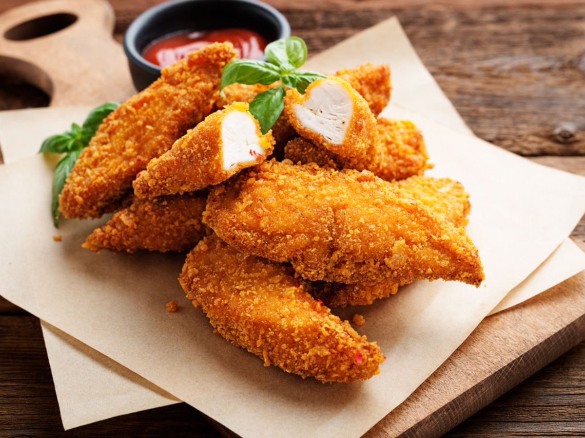 Breaded chicken with herbs and a cup of ketchup