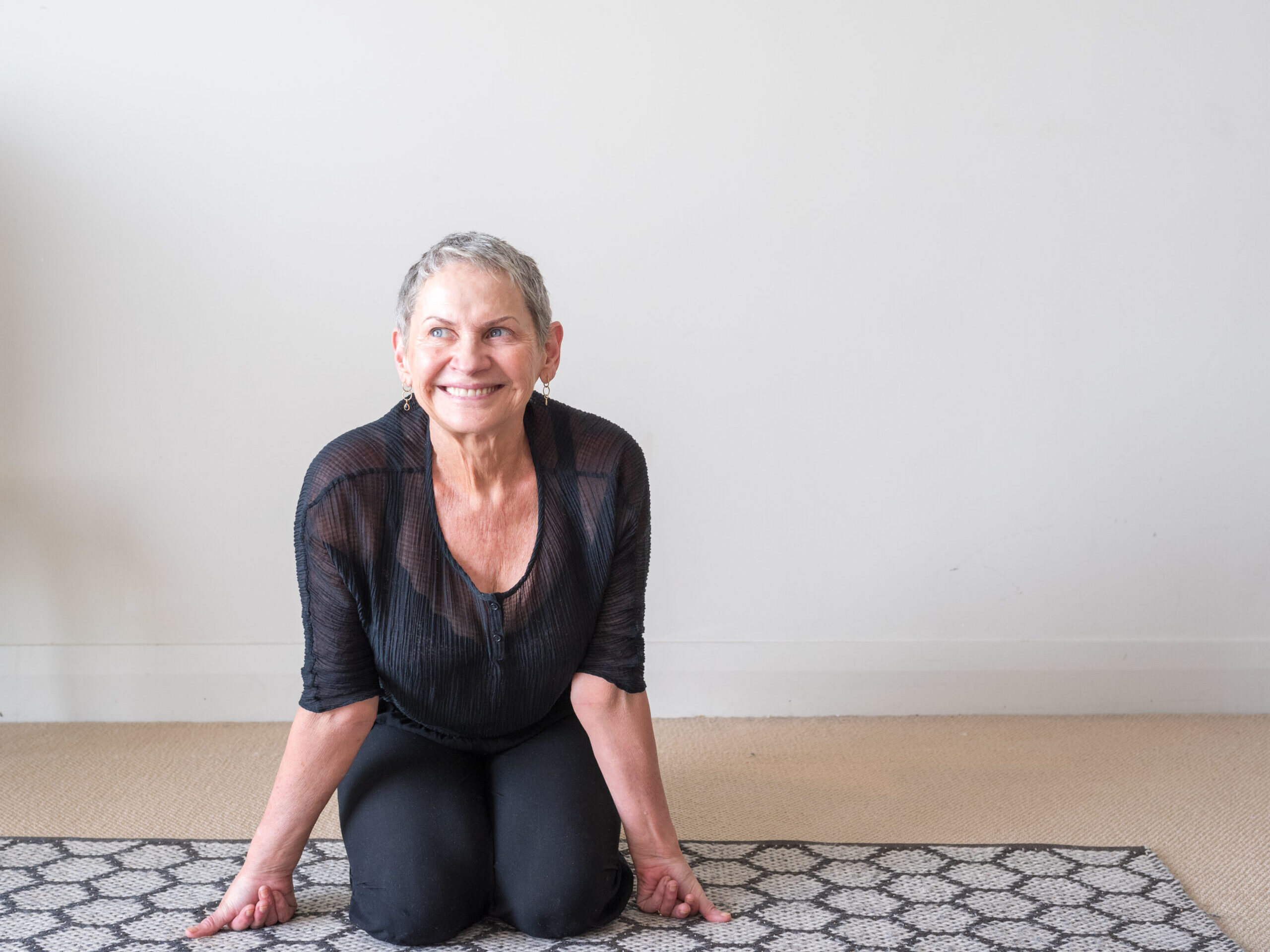 woman with short gray hair kneels on the ground