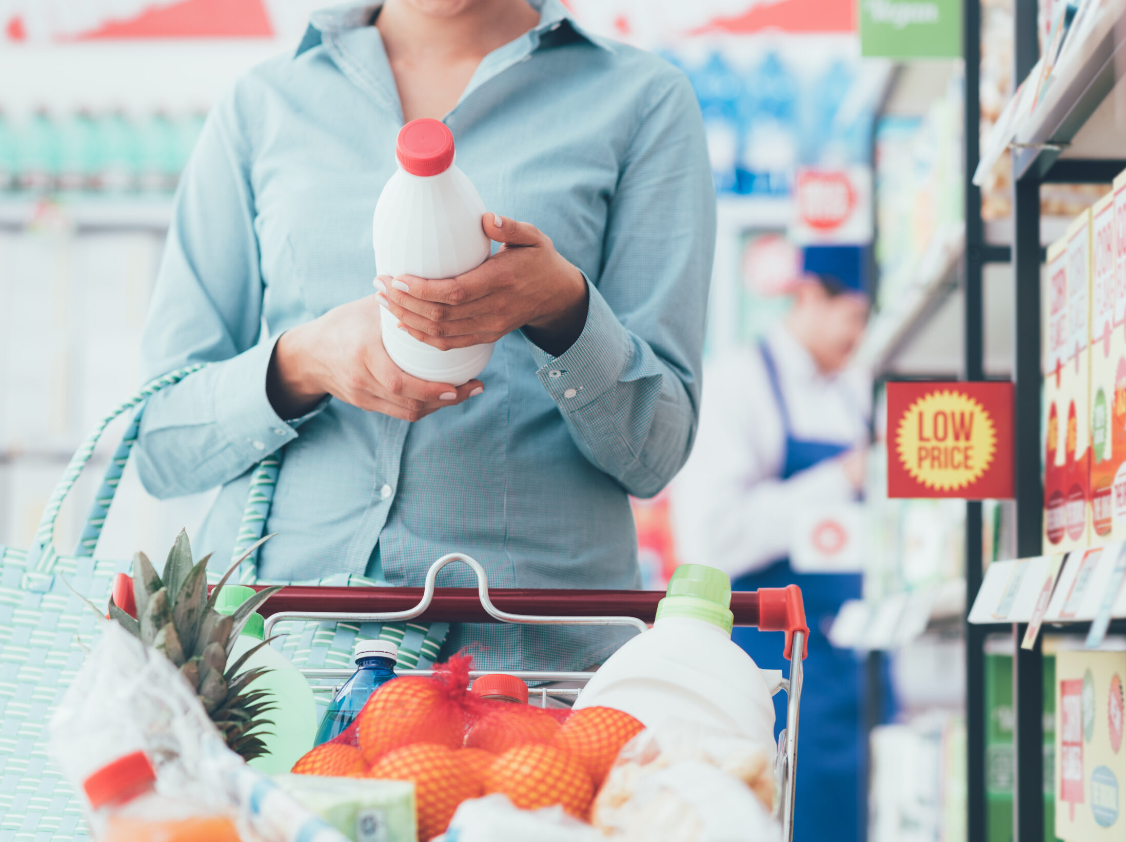 A woman reading the label on a beverage bottle while grocery shopping