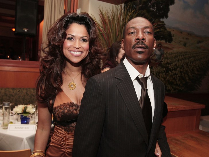 Tracy Edmonds (L) in brown dress smiling next to Eddie Murphy, who is wearing a classic black suit and tie