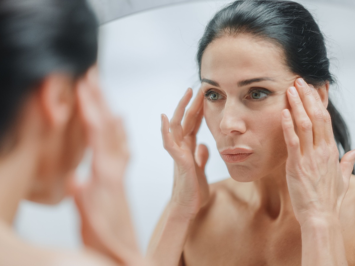 a woman with straight black hair looks in the mirror