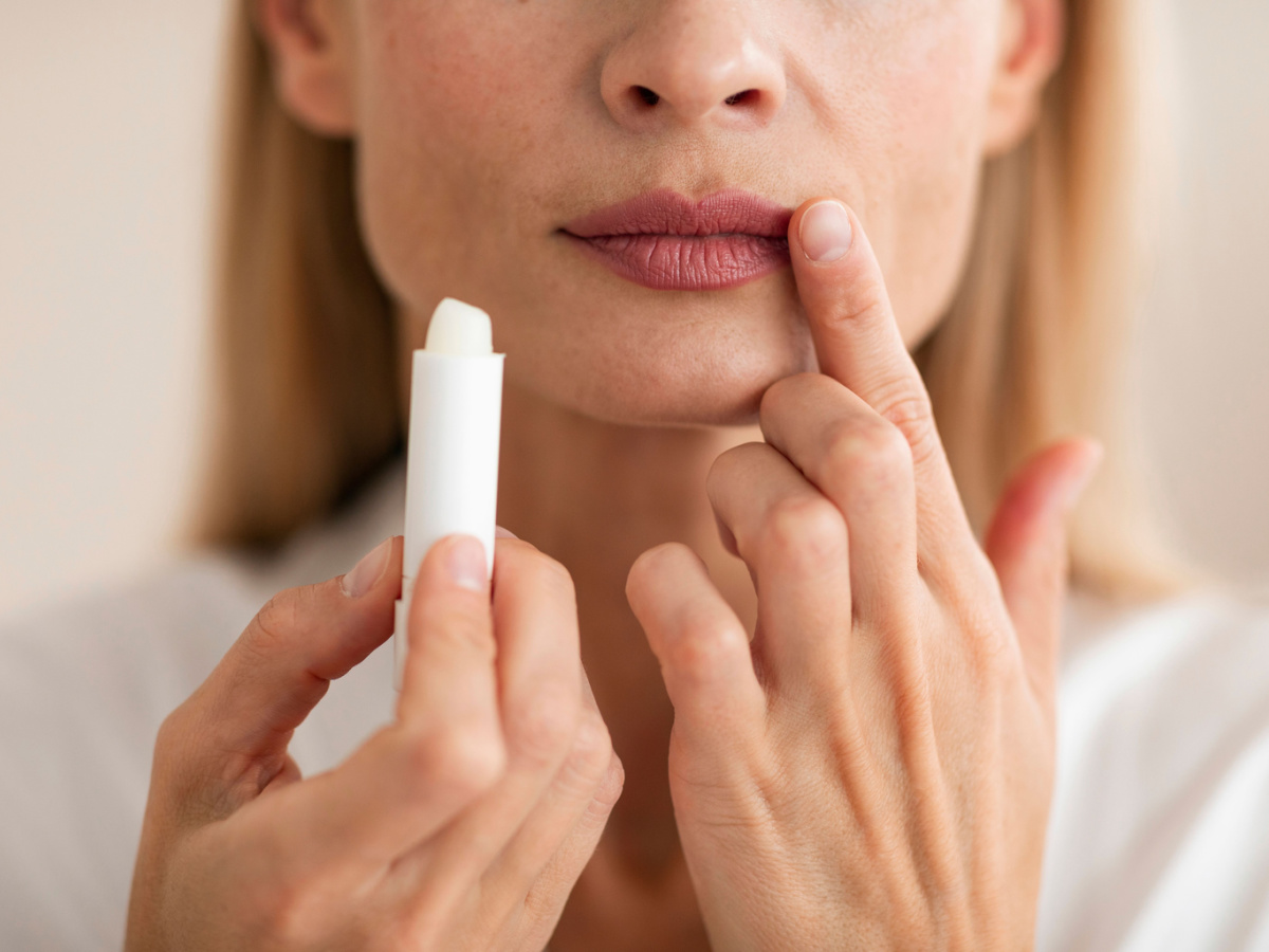 A blond woman holds a stick of lip balm