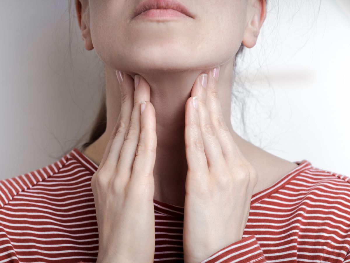 Sick woman holding her hands to her sore throat