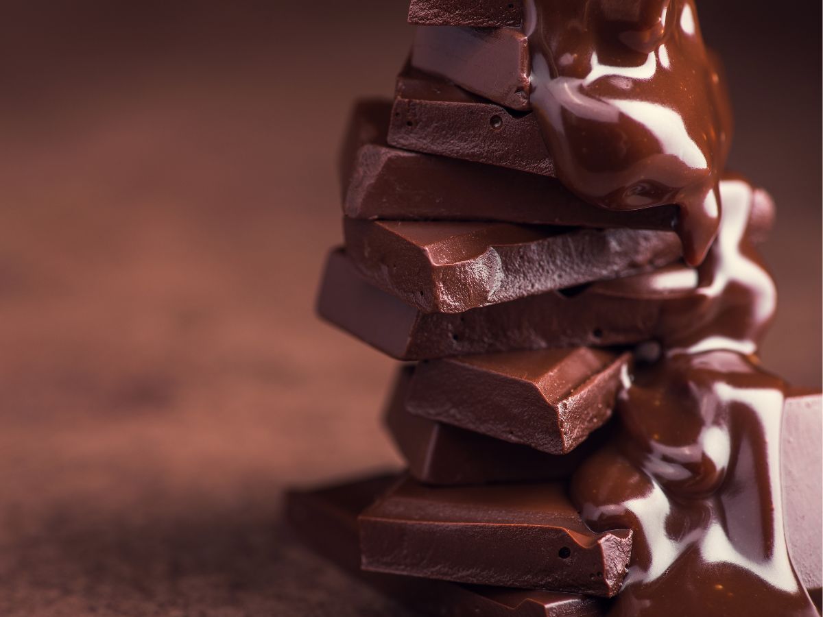 Melted chocolate being poured onto pile of chocolate pieces