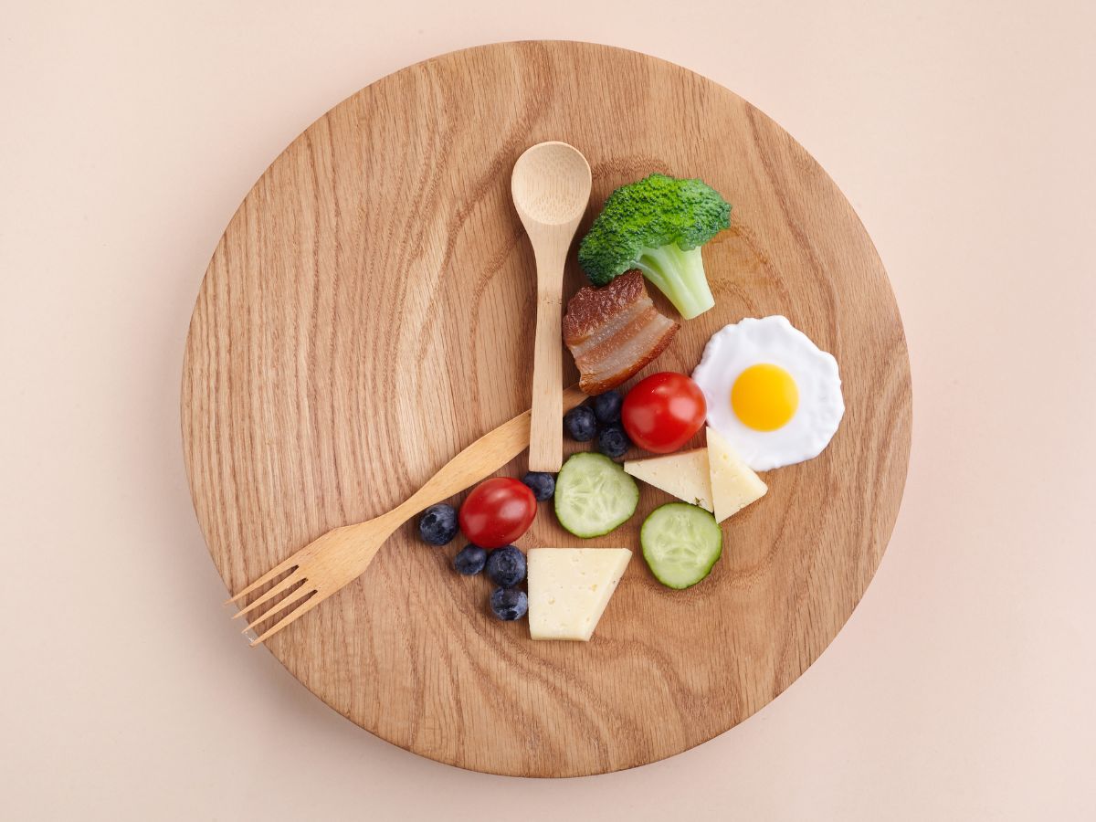 Dinner plate with fork and knife arranged like clock hands, food on specific part of the plate