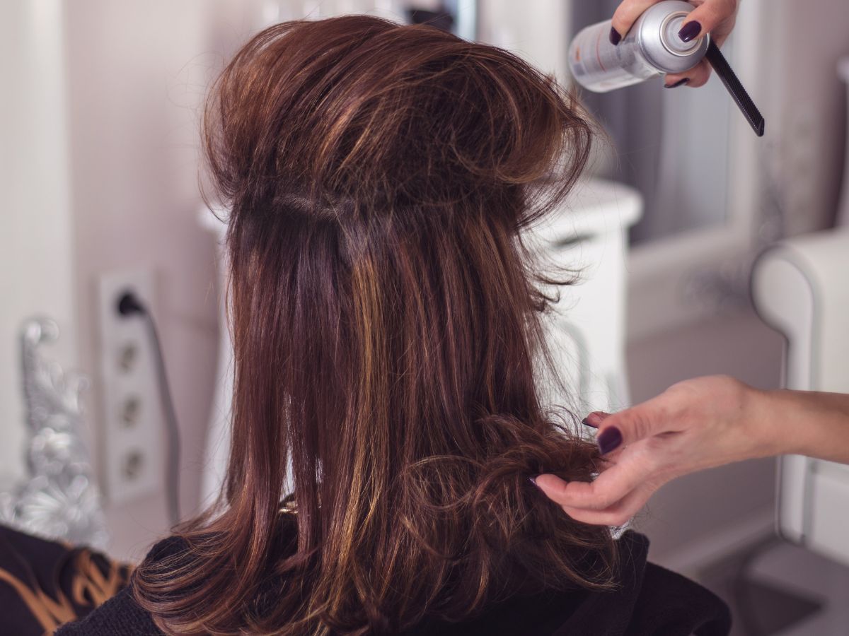 Hairstylist using spray product to add volume to client's hair